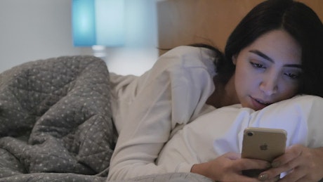 Girl lying down chatting on her cell phone before sleeping