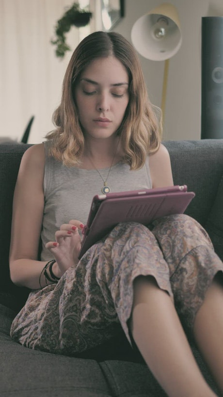 Girl lying in an armchair using an iPad.