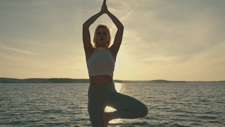 Girl making yoga in a beautiful sunset at a beach.