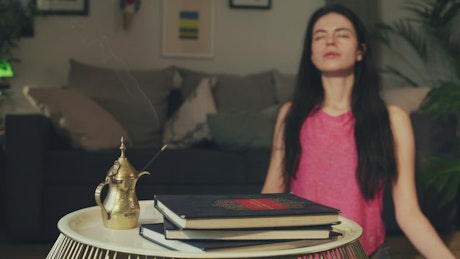Girl meditating in her room with incense.