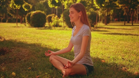 Girl meditating in yoga pose in a park.