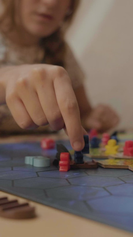 Girl moving small figures from a board game.