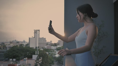 Girl on a video call standing on a balcony at sunset