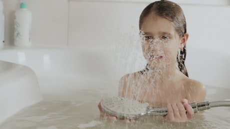 Girl playing with water while taking a bath.