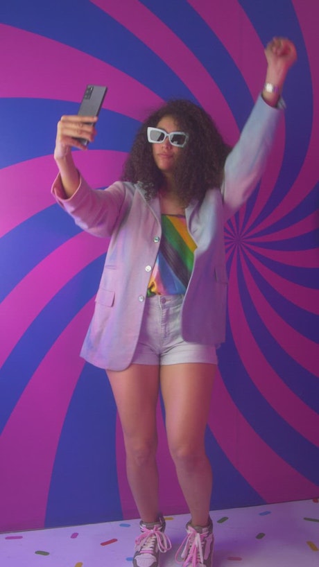 Girl recording herself dancing with a colorful background.