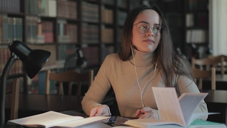 Girl rubs head in pain while studying late in library