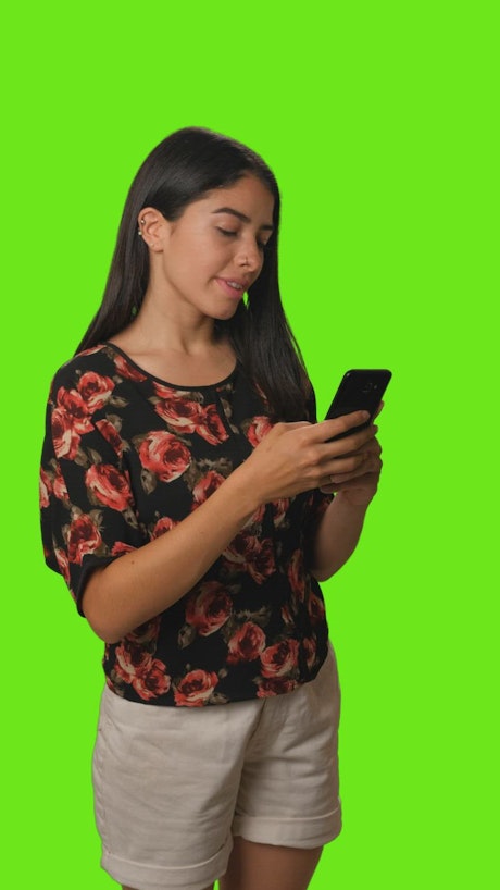 Girl sending a selfie by cell phone on a green background.