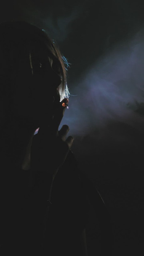 Girl smoking in the shadows with a backlight.