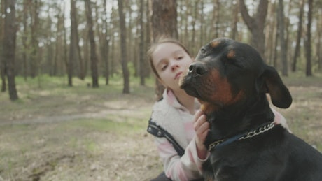 Girl stroking her dog in the forest.