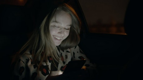 Girl texting in the back seat of a car