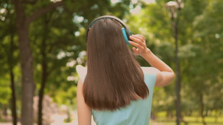 Girl walking in nature with music on her headphones.