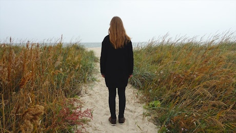 Girl walking towards the seashore.
