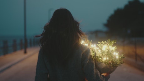 Girl walks alone with a luminous bouquet of flowers.
