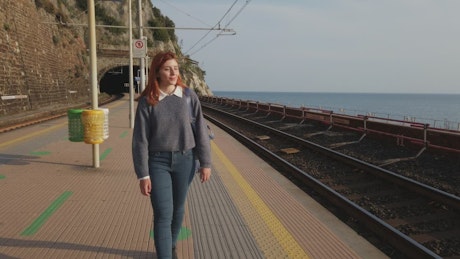 Girl walks at the train station on the seaside.