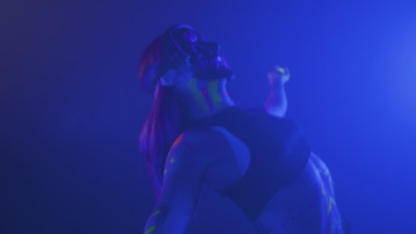 Girl with a mask dancing under a party light