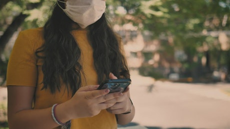 Girl with a mask on the street answers a call.