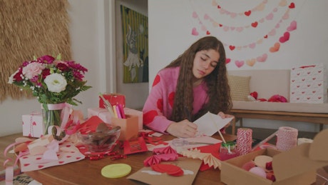 Girl writing on a decorated valentine card.