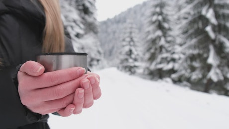 Girl's hands holding a cup of tea in winter.