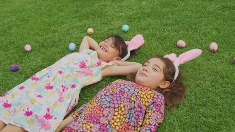 Girls lying between Easter eggs.