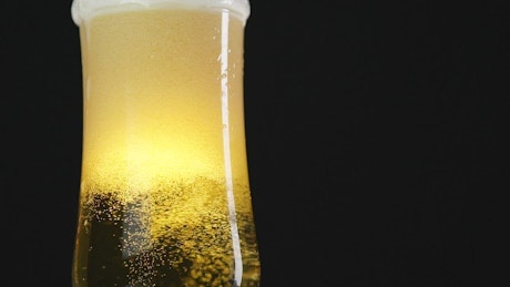Glass of beer on a black background, in detail.