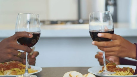 Glasses with wine bumping into a toast at a romantic dinner