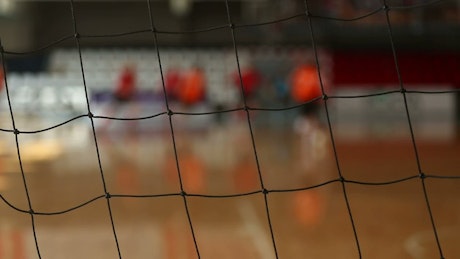 Goalkeeper net close up with a game in the background.