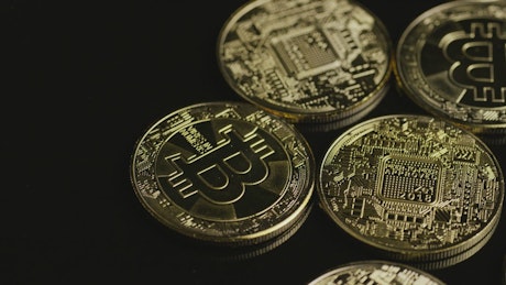 Golden bitcoin coins rotating on a black surface