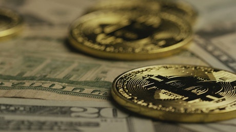 Golden bitcoin coins rotating over dollars.