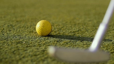 Golf club hitting a ball on a golfing range.