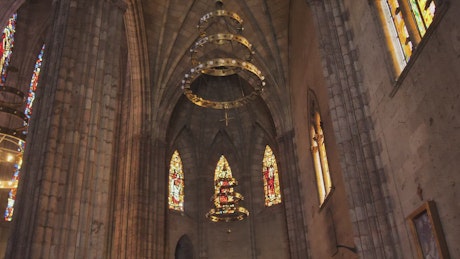 Gothic church inside with colorful stained glass windows and a large chandelier.