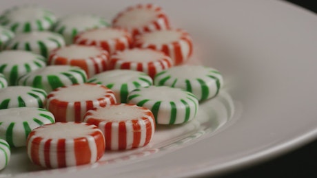 Green and red candies rotating on a white plate.