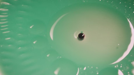 Green liquid with bubbles, close up.