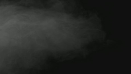 Grey smoke cloud drifts on black background