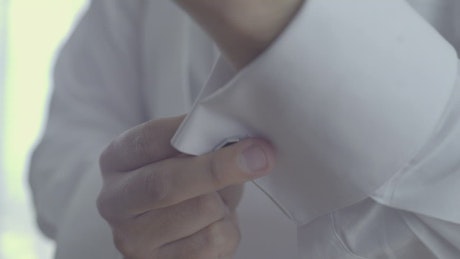 Groom placing cufflinks on his sleeves