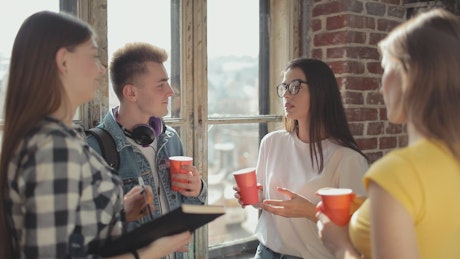 Group of friends share drinks and ideas by window