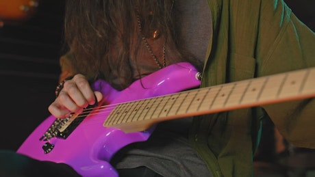 Guitarist tuning a pink guitar.