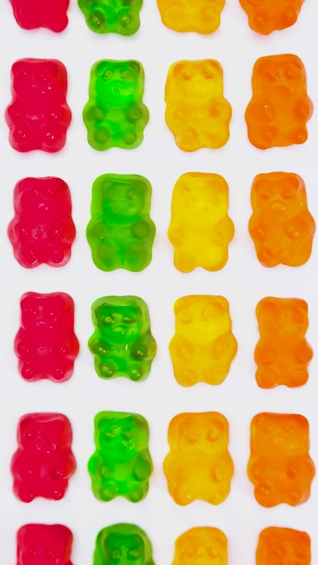 Gummy bears lined up on a white background.
