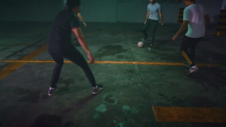 Guys playing football in a parking lot.