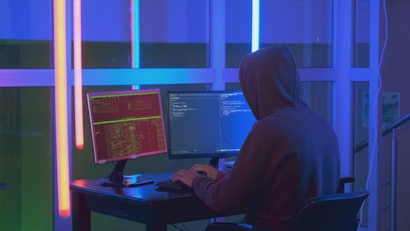 Hacker writing code on a computer screen.