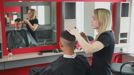 Hair stylist cuts a man's hair.