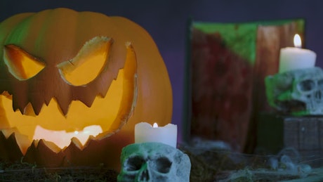 Halloween pumpkin with cobwebs, candles, gravestones and smoke around