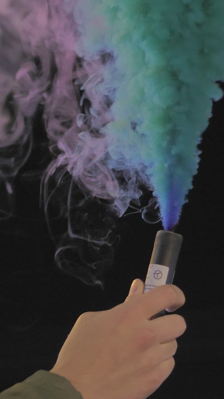 Hand holding a multicolored smoke bomb.