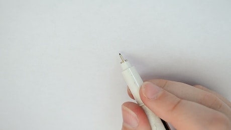 Hand of a person drawing a flower with stylograph.