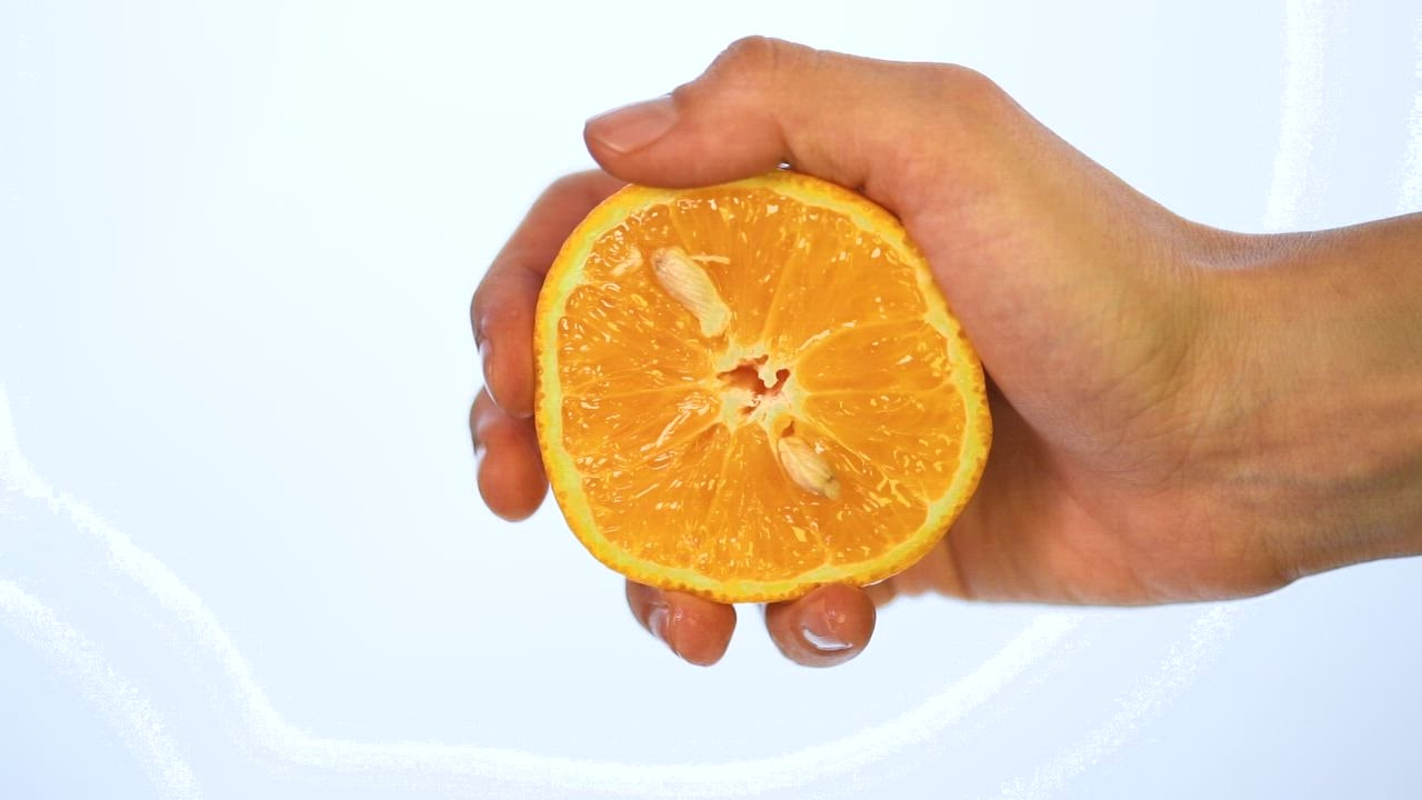 Hand of a person squeezing an orange on a light ba live draw super wuhan ckground