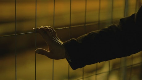 Hand on a wire fence by night.