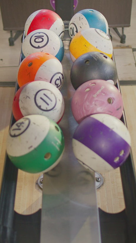 Hand selecting bowling balls from the tray.