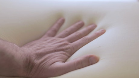 Hand touches the softness of the memory foam mattress.