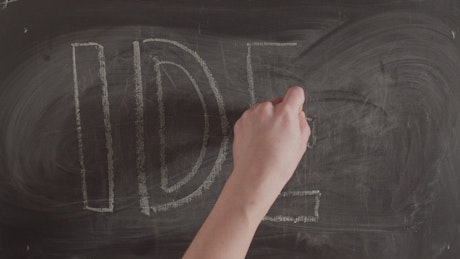Hand writing 'Idea' on a blackboard.
