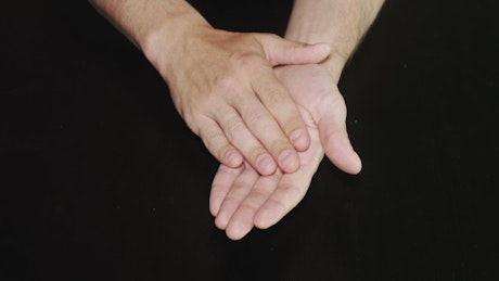 Hands clapping against a dark background.