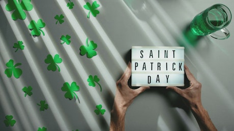 Hands leave a St. Patrick's Day sign on a festive background.